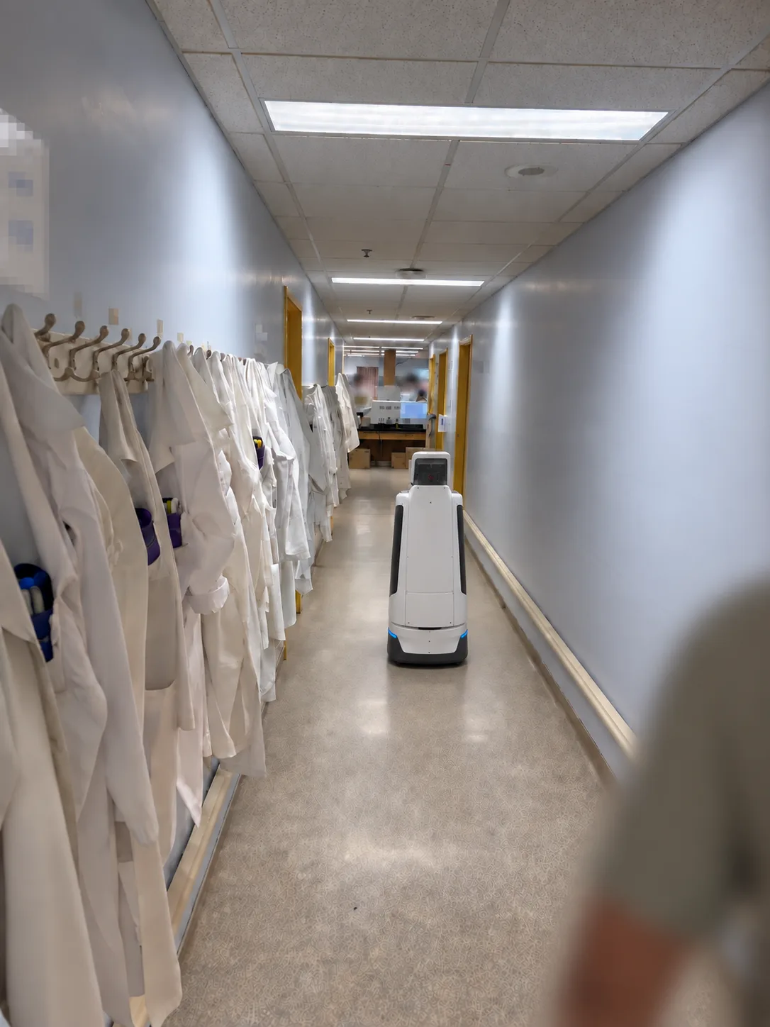 AI assistant robot navigating an anonymized workplace corridor